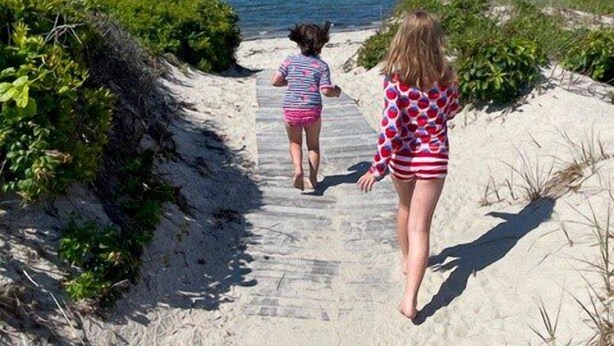 A pathway leading to the beach with vegetation on both sides.