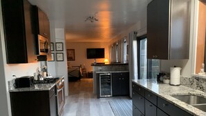 Una cocina moderna con armarios oscuros, horno empotrado, microondas y encimera de granito.
