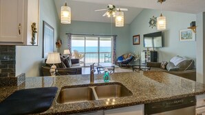 A kitchen with granite countertops, a double sink, and a dining area with a view of the ocean. - 2 Bedroom Direct Oceanfront (Surf City)