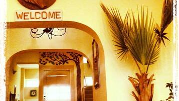 A hallway with a 'WELCOME' sign, a clock, and a staircase.