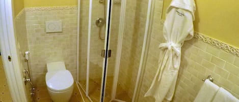 A bathroom with a glass-enclosed shower, a toilet, and a robe hanging on a hook.