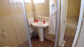 Un baño con inodoro, bidé, lavabo y ducha con mampara de vidrio.
