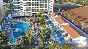 Un hotel con una piscina grande, varios balcones y vistas al océano.