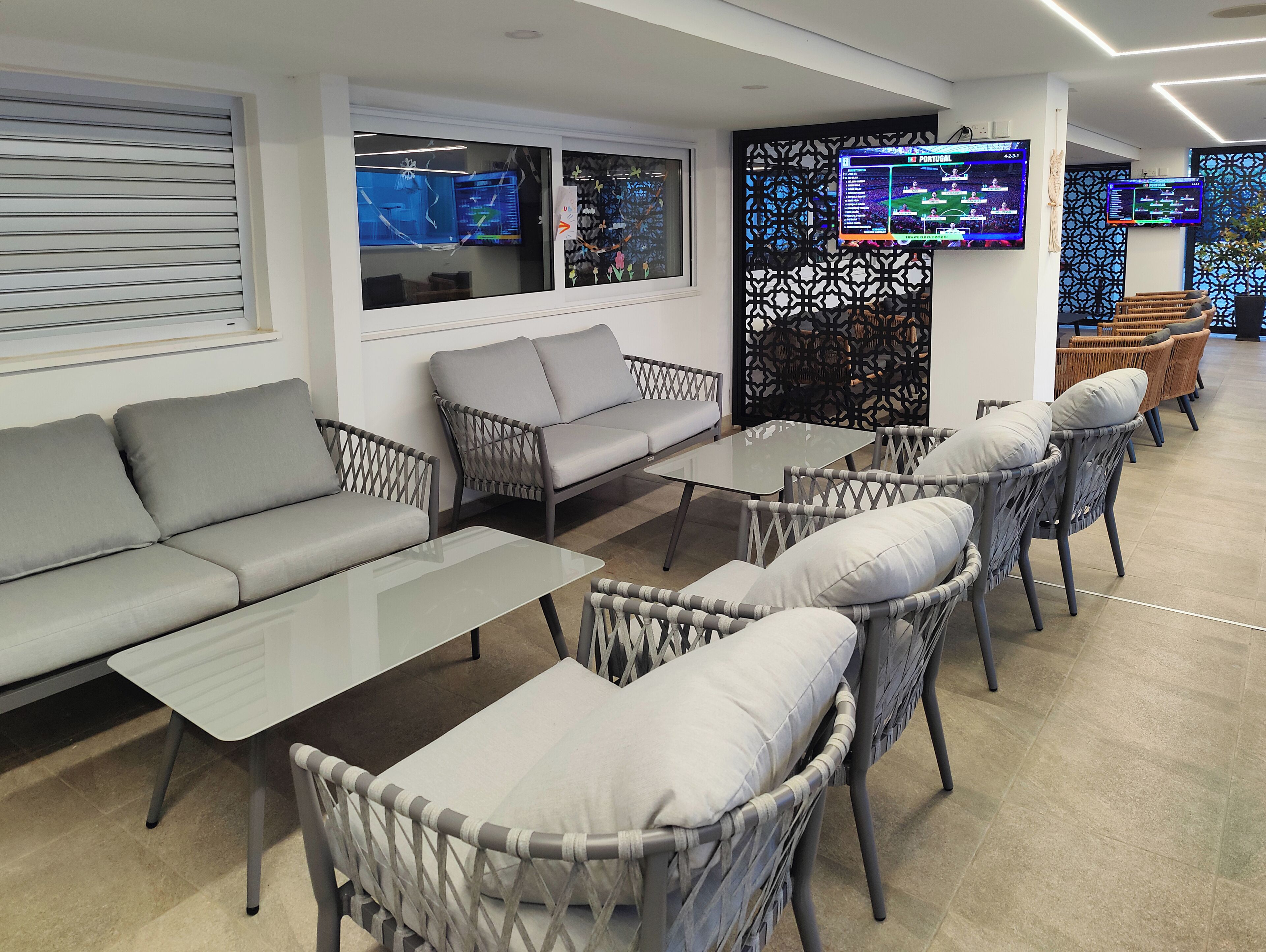 Un espacio lounge moderno con un sofá, sillas y una mesa de vidrio.