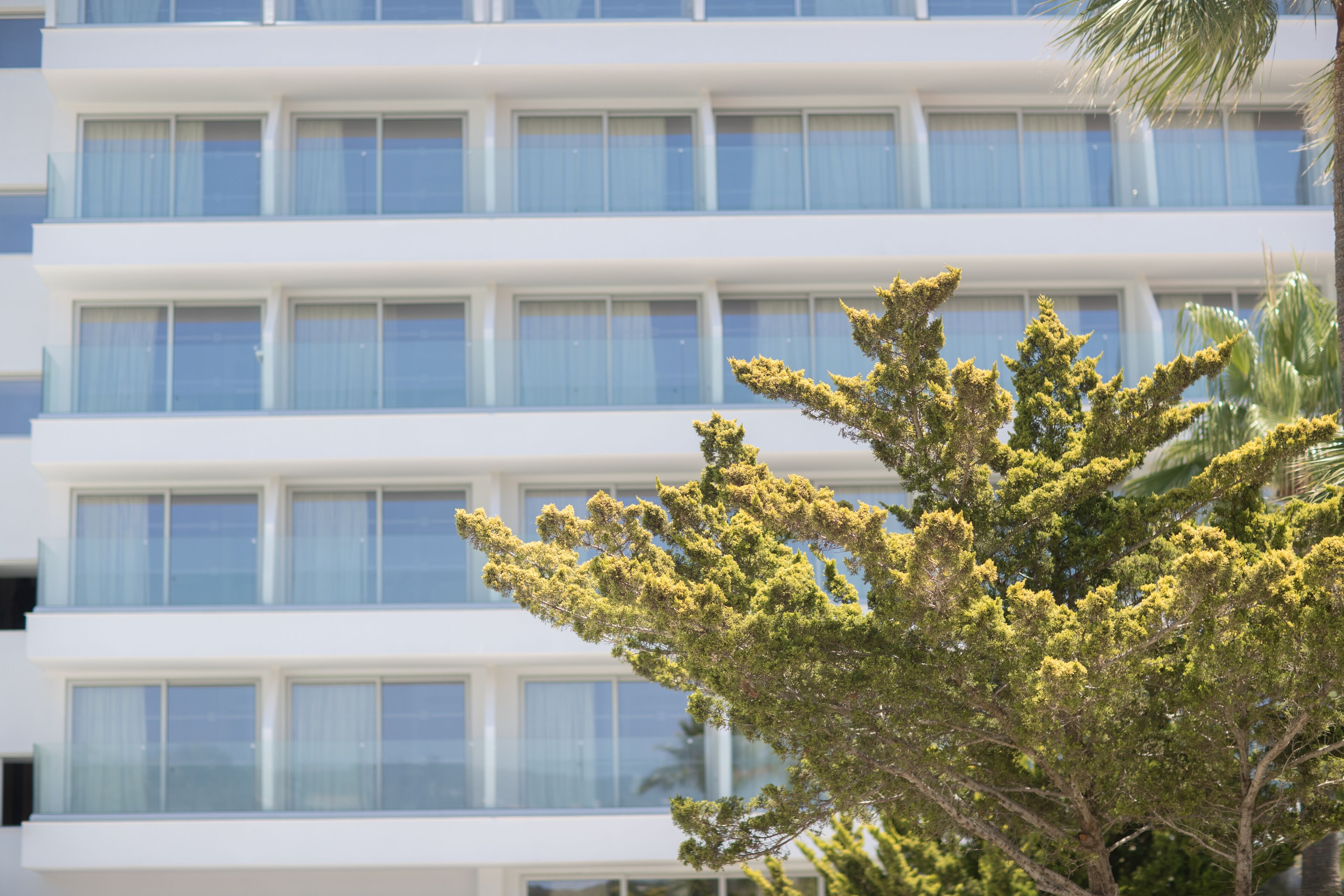 Un edificio de varios pisos con un diseño arquitectónico moderno, que cuenta con una serie de balcones y ventanas amplias.