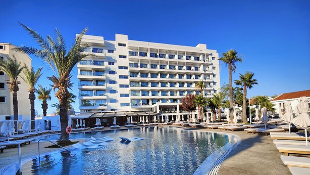 Un hotel con piscina, palmeras y un edificio de varios pisos.