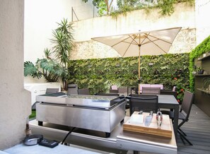 An outdoor patio with a grill, dining table, chairs, and an umbrella. - Loft, 42 m² terrace, just a stone's throw from the Croisette (Cannes)