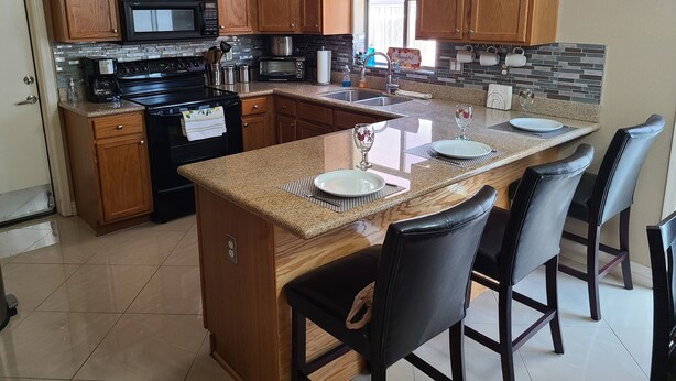 Una cocina moderna con armarios de madera, encimera de granito y una isla central con taburetes de bar.