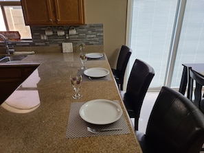 Enjoy meals in the kitchen with a granite countertop, wooden cabinets, and a dining area with black leather chairs.