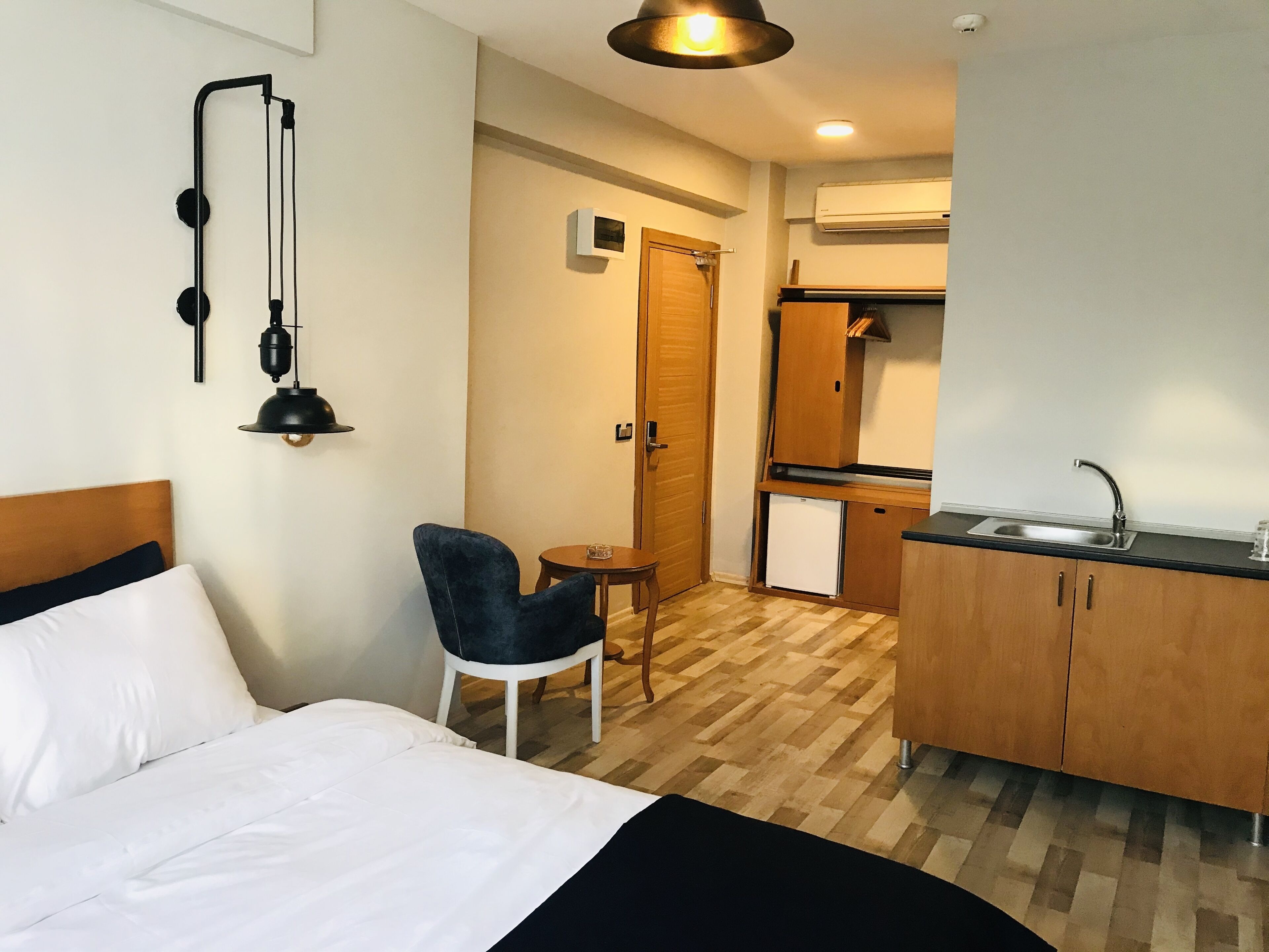 A hotel room with a bed, a desk with a sink, a chair, and a small table.