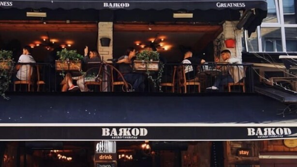 An outdoor seating area of a restaurant with tables and chairs, a sign reading "BAJKOD", and a chalkboard menu. - Barkod Hotel (Istanbul)