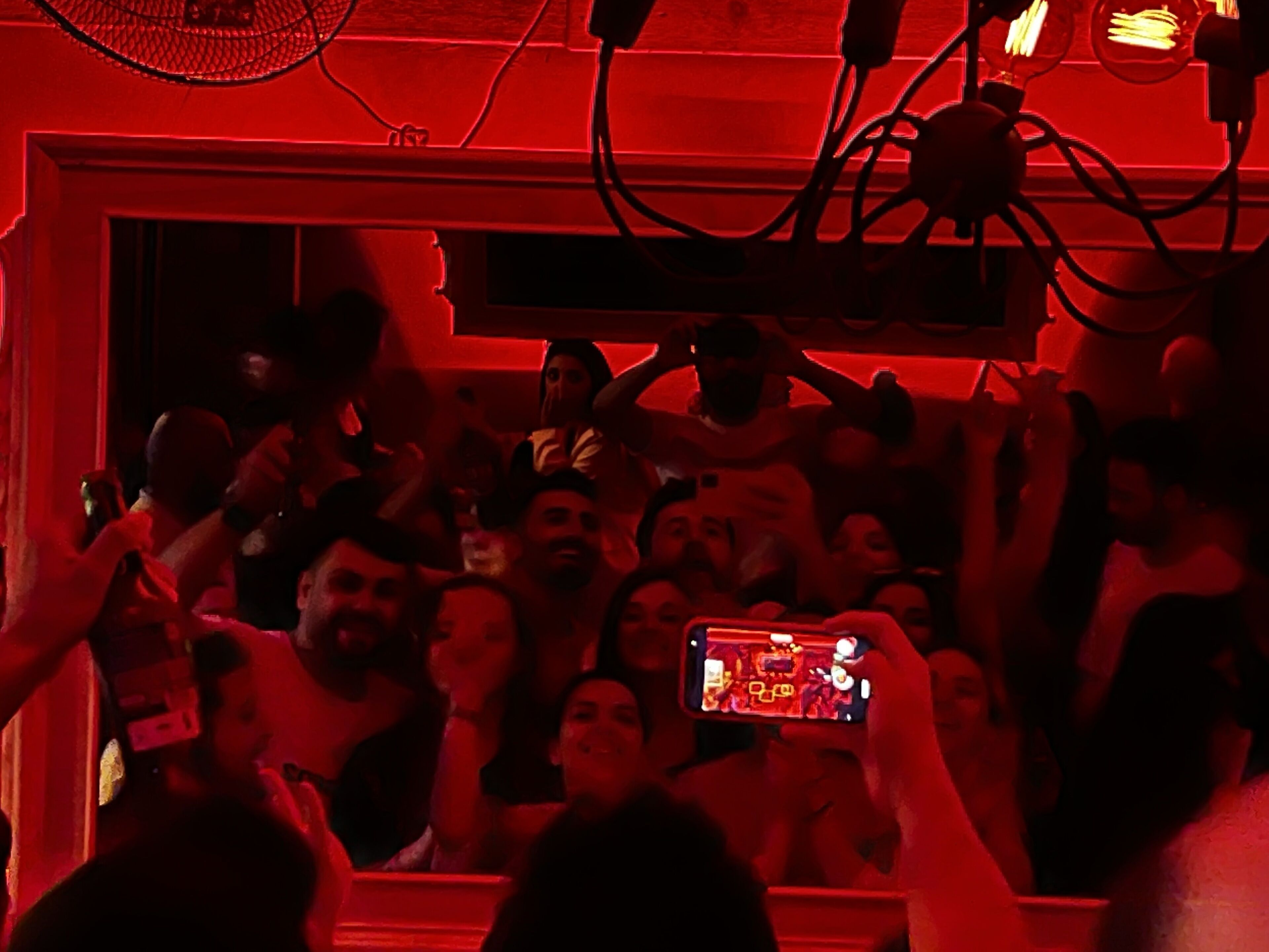 Ein voller Innenraum, in dem Menschen ihre Handys hochhalten, vermutlich bei einem Konzert oder einer Veranstaltung.