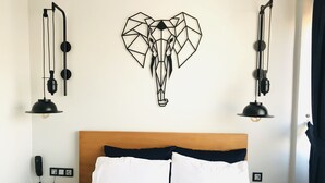 A hotel room with a wooden headboard, white bedding, a geometric wall art of an elephant, and two black pendant lamps. - Barkod Hotel (Istanbul)