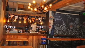 A bar with wooden furniture, a bar counter with bottles, and a mural on the wall. - Barkod Hotel (Istanbul)