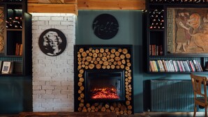 A cozy room with a fireplace, bookshelves, and a wooden chair. - Barkod Hotel (Istanbul)