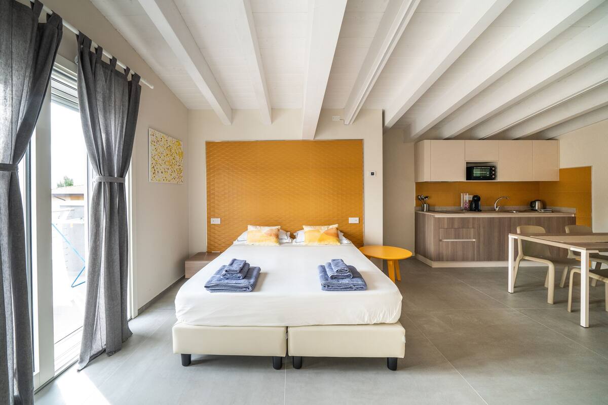 Een hotelkamer met een groot bed, een kitchenette en een eettafel.