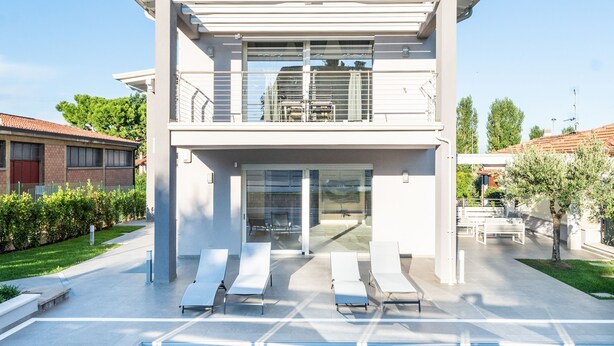 A modern two-story house with a swimming pool, lounge chairs, and a covered patio area. - A Casa di Sabina (Desenzano del Garda)