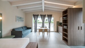 A modern room with a bed, a sofa, a dining table with chairs, and a large wooden wardrobe. - A Casa di Sabina (Desenzano del Garda)