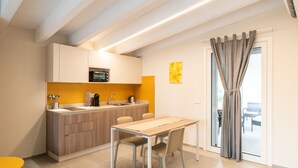 A modern kitchen with a dining area, featuring a wooden table, chairs, and a built-in microwave. - A Casa di Sabina (Desenzano del Garda)