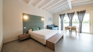 A modern bedroom with a large bed, a bench, a desk, and a chair. - A Casa di Sabina (Desenzano del Garda)