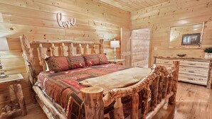 Ein rustikales Schlafzimmer mit Holzboden, einem Bett, einer Kommode und einer Wandlampe.