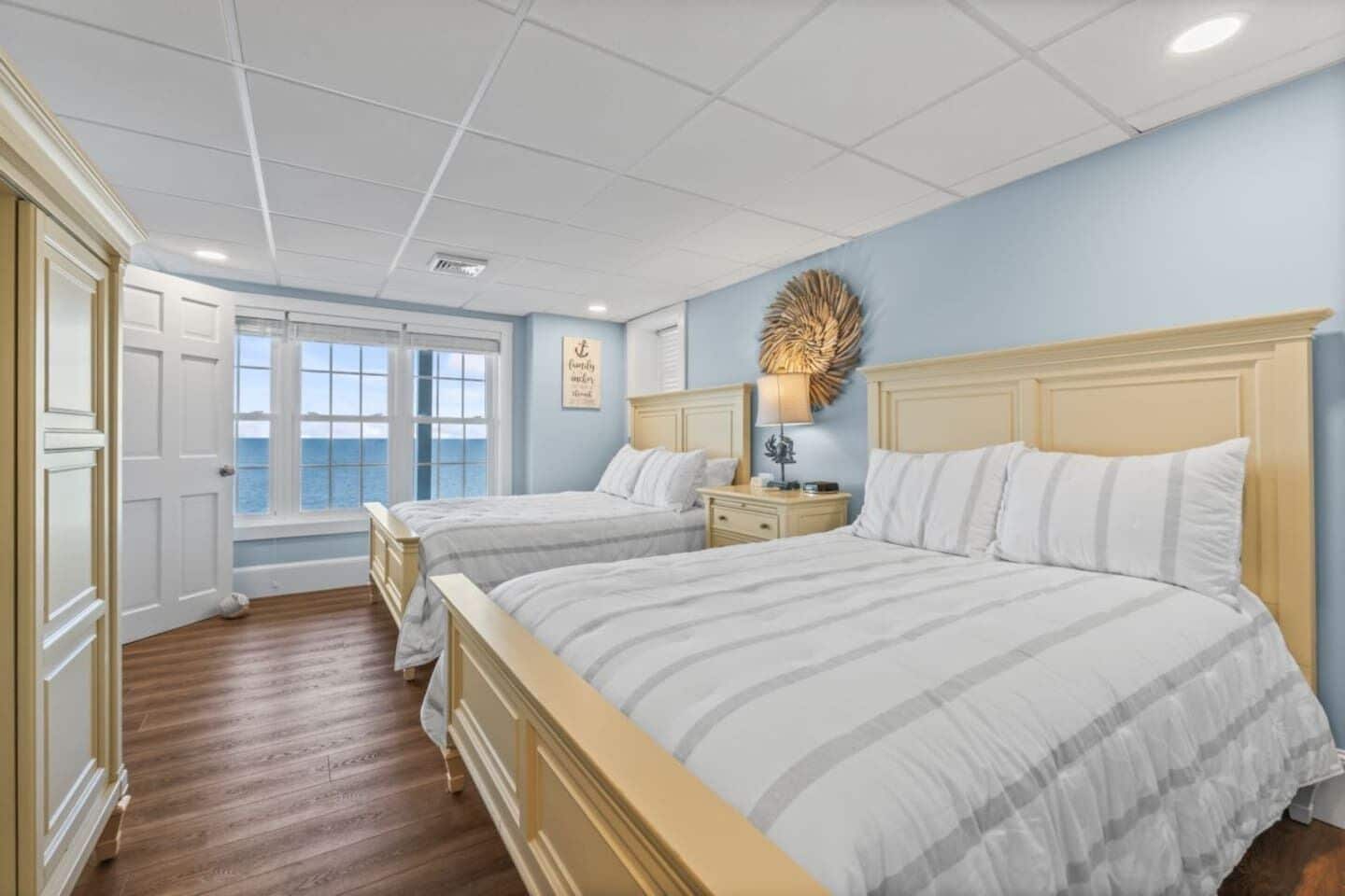 A bedroom with two beds, a window with a view, a decorative wall piece, and a bedside table with a lamp.