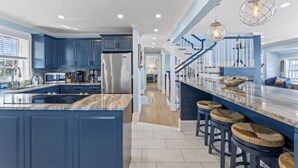 Una cocina moderna con armarios azules, una isla grande y una zona de bar con taburetes.