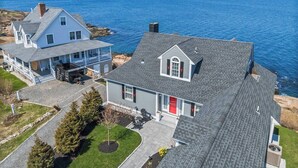 Una casa frente al mar con una amplia terraza, un patio cubierto y vistas al océano.