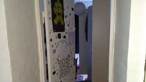En smal hall med en vit dörr som är dekorerad med olika klistermärken och teckningar.