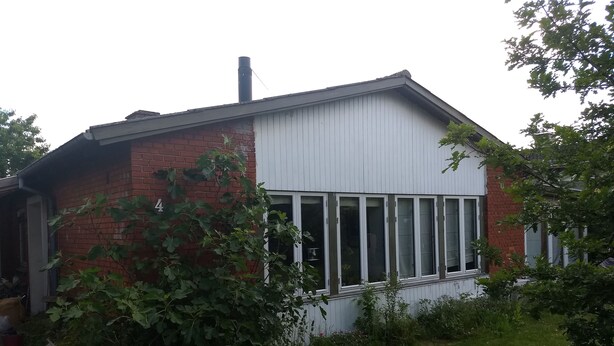 Ett tvåvåningshus med en fasad av tegel och en vit överdel.