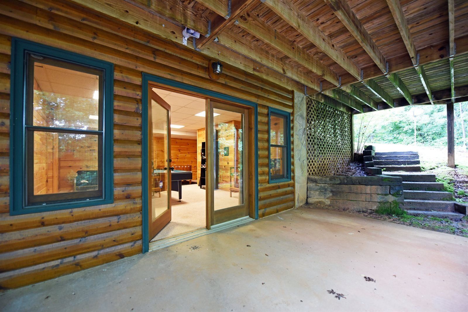A log cabin with a glass door entrance leading to a room with a pool table.