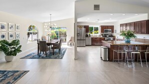 Una cocina amplia con electrodomésticos modernos, un comedor con un ventanal grande y un espacio de sala de estar con una araña.