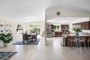 Uma cozinha espaçosa com eletrodomésticos modernos, uma sala de jantar com uma janela ampla e uma sala de estar com um candelabro.