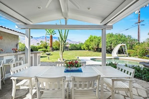 Eine Terrasse im Freien mit Pool, weißer Möbel und Blick auf Berge.