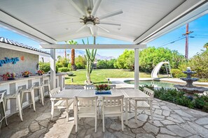 Eine überdachte Terrasse mit Pool, Sitzgelegenheiten im Freien und Blick auf die Berge.
