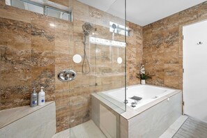 A modern bathroom with a glass-enclosed shower, a standalone bathtub, and marble walls. - Palm Springs home with large private backyard and spectacular Mountain Views (Palm Springs)