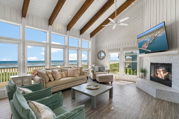 A spacious living room with a fireplace, large windows, and a television.