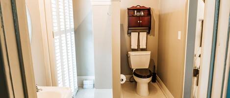 A compact bathroom with a toilet, a small cabinet, and a bathtub.