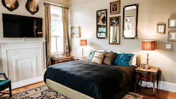 Un dormitorio con una cama grande, un televisor montado encima y una chimenea.
