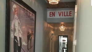 Un pasillo con un cartel enmarcado, una araña y un letrero que dice 'EN VILLE'.