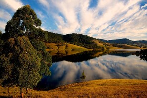 Eine friedliche Landschaft mit einem stillen See, der den Himmel und die umliegenden Bäume spiegelt.
