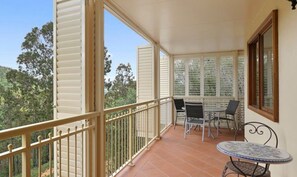 Ein Balkon mit Tisch und Stühlen, einer Brüstung und Blick auf Bäume.