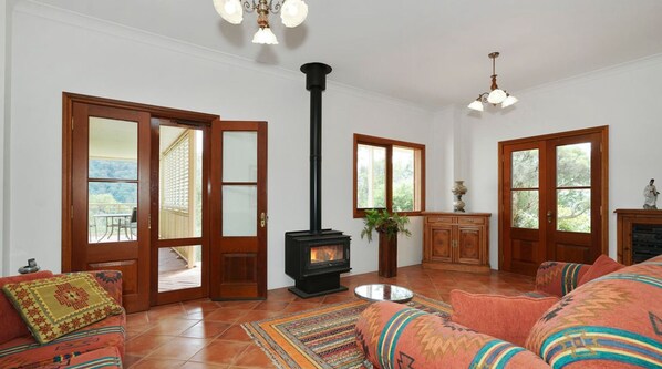 A spacious living room with a fireplace, large windows, and a balcony. - Home with stunning views in Hunter Valley. 10pp hot tub spa & Tesla charger (Mount Rivers)