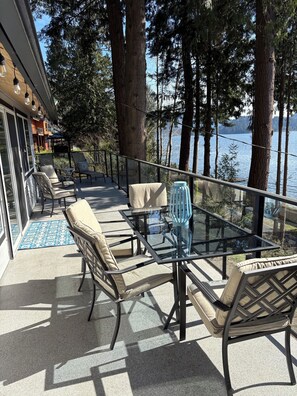 Un espace extérieur aménagé avec des chaises et une table, offrant une vue sur un lac et entouré d’arbres.