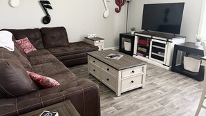 A modern living room with a brown leather sofa, a wooden coffee table, and a TV on a stand. - Cumberland Cottage, 1 level house just off I-24, near Murfreesboro and Nashville (Murfreesboro)