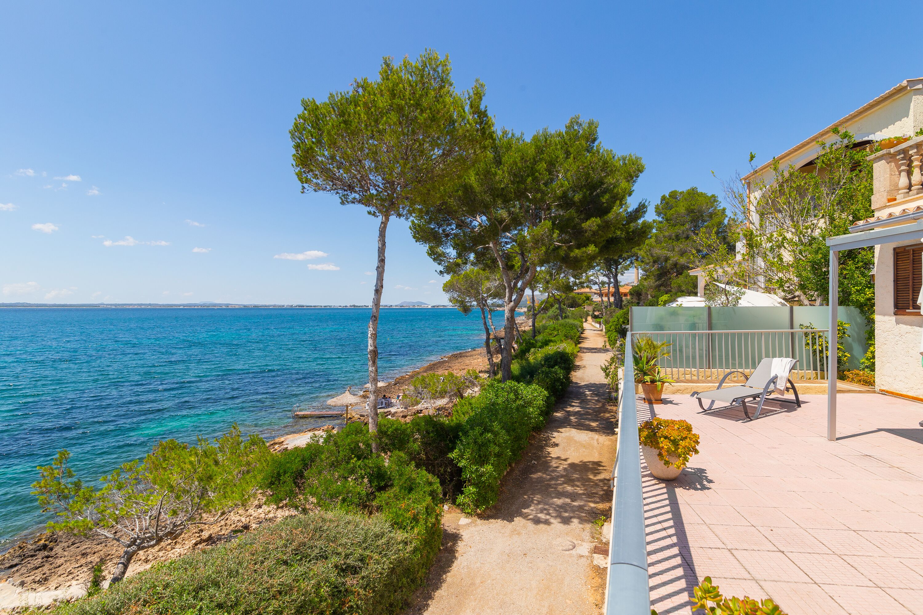 A coastal property with a paved walkway, outdoor seating, and a view of the sea.
