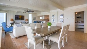 A spacious living area with a dining table surrounded by chairs, a sofa, and a TV mounted on the wall. - Ocean Front! Entire Top Level + View Deck + AC (San Diego)