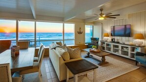 A spacious living room with a large window overlooking the ocean, a ceiling fan, a television, and a cozy seating area. - Ocean Front! Entire Top Level + View Deck + AC (San Diego)