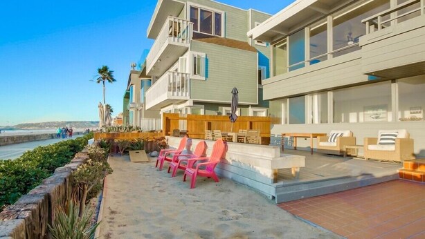 Une propriété située en bord de mer, dotée d’un patio avec coin salon extérieur et piscine.