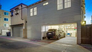 Un bâtiment à deux étages avec une porte de garage ouverte, laissant apercevoir une voiture à l’intérieur.